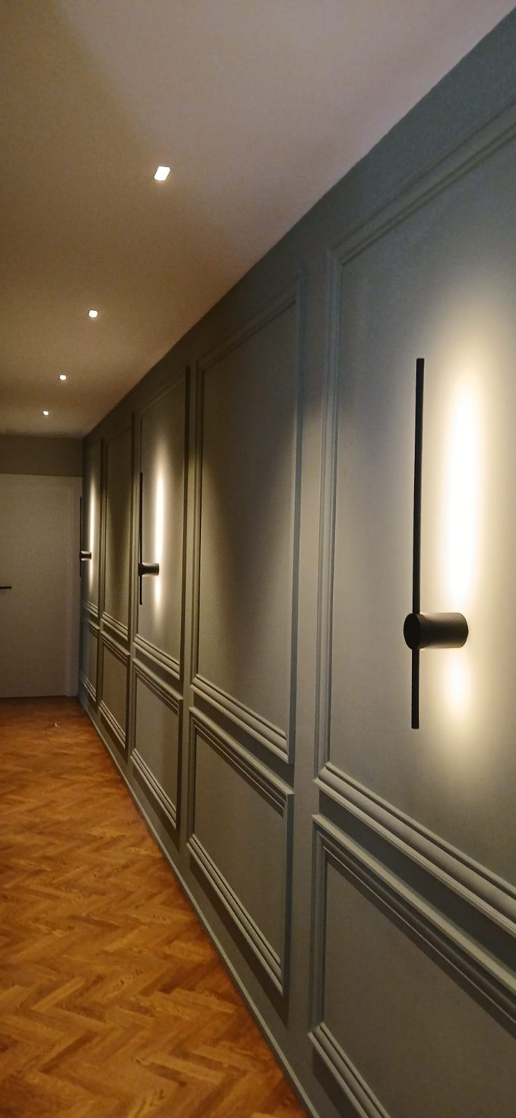 Pasillo con apliques de pared y focos empotrados