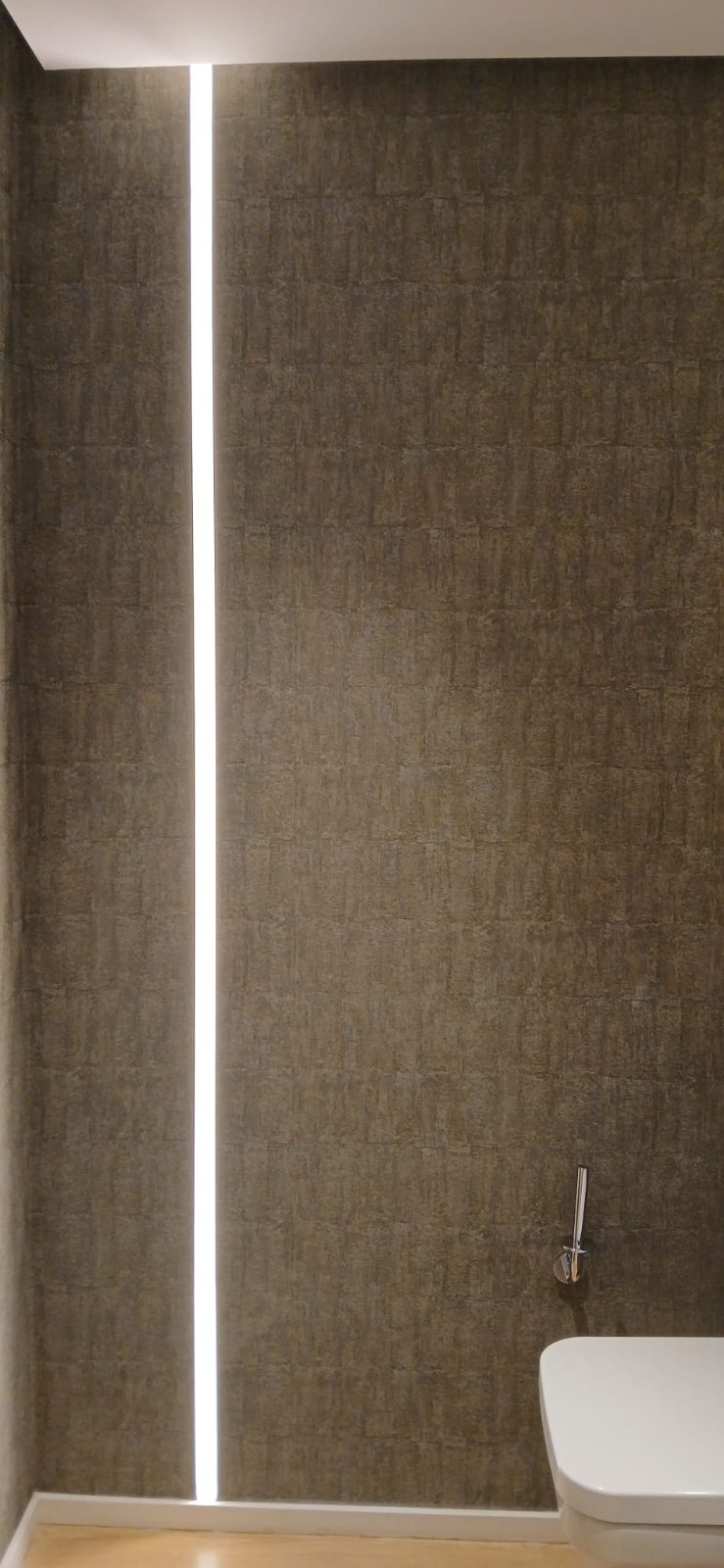 Baño con una línea vertical de luz LED empotrada en el revestimiento de pared