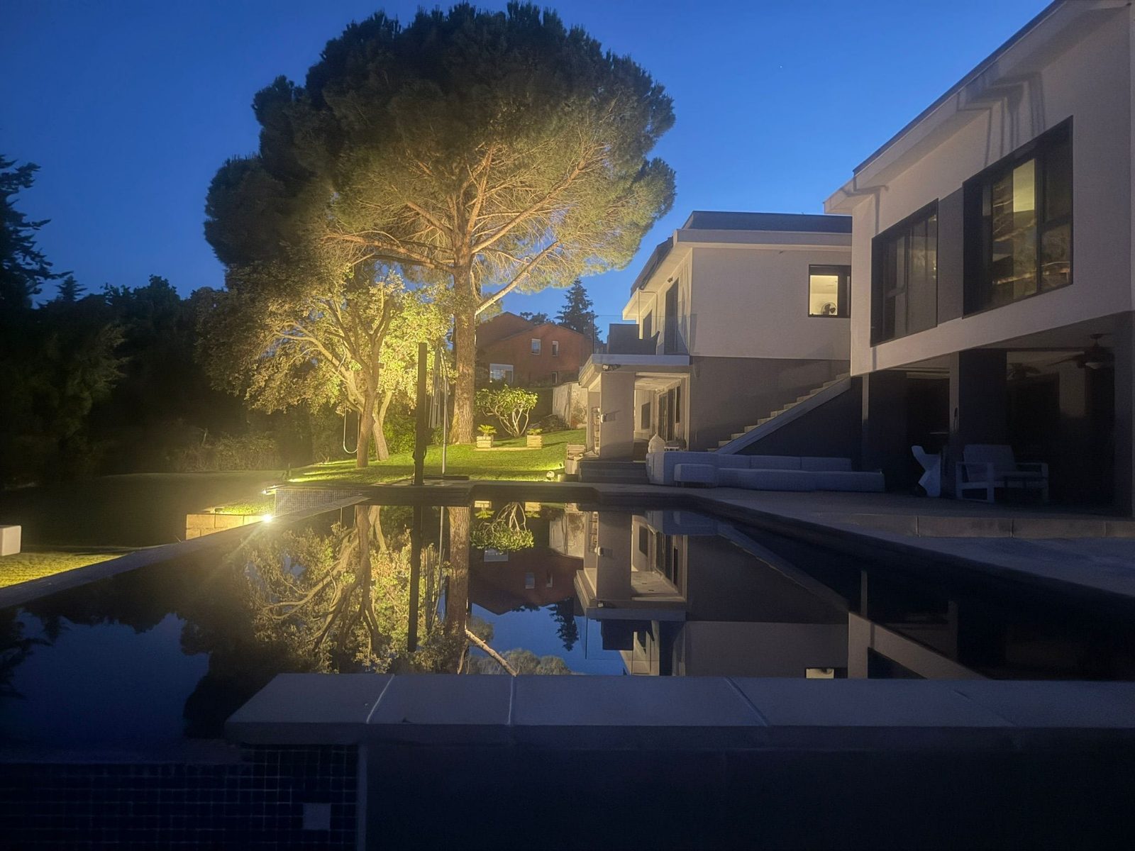 Jardín con piscina iluminado de noche