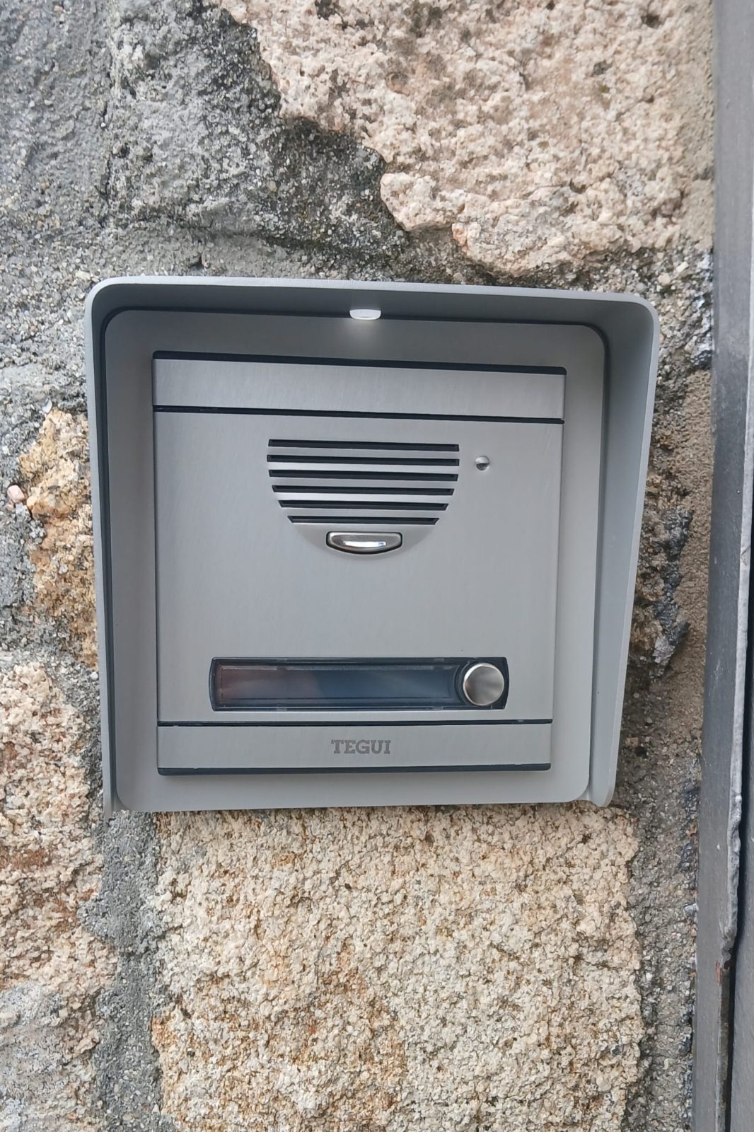 Placa de calle de videoportero Tegui instalada en un muro de piedra